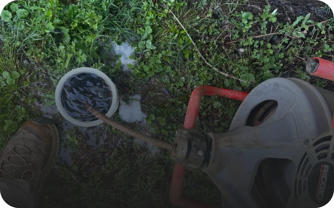 Drain cleaning machine in use on grass.