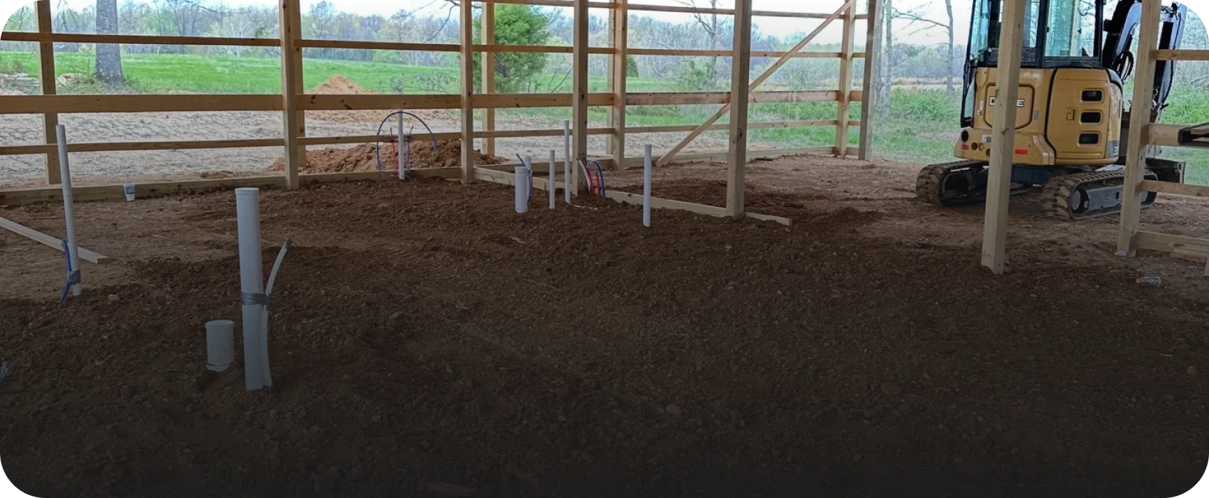 Construction site with excavator and pipes.